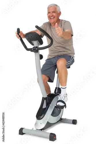 Senior man gesturing thumbs up on stationary bike