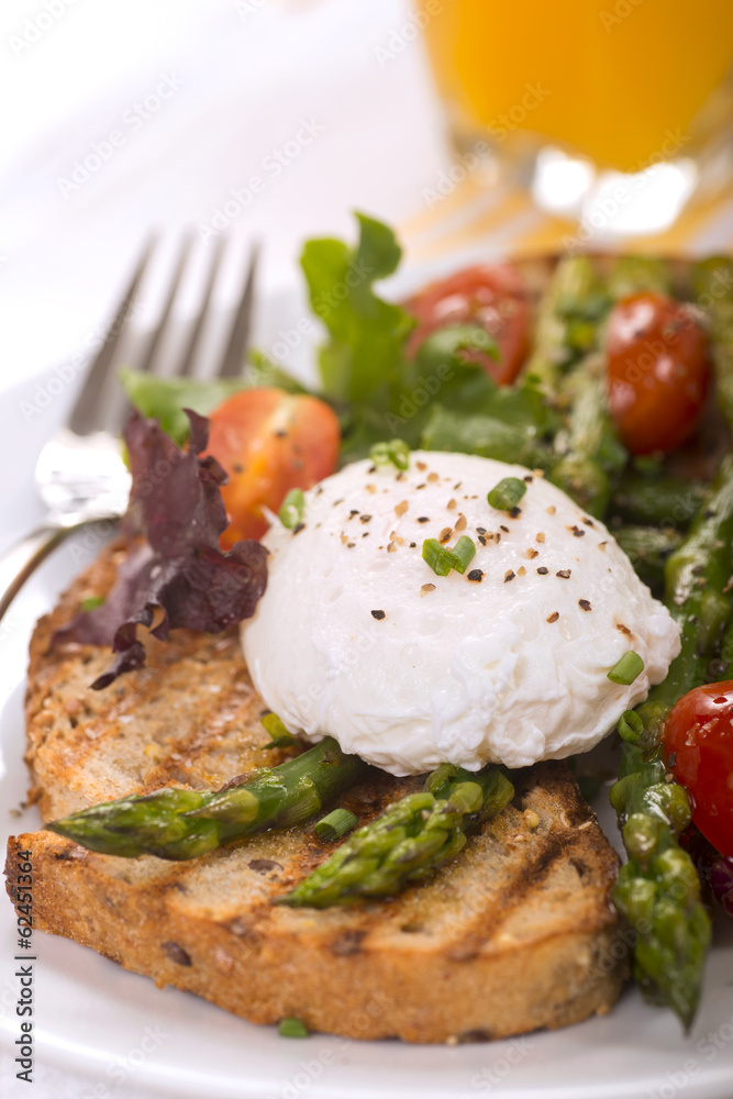 Poached egg on toasted bread with asparagus, tomatoes and greens Poached egg on toasted bread with asparagus, tomatoes and greens