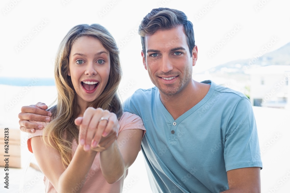 Obraz premium Cheerful woman showing engagement ring besides man