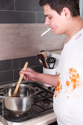 Handsome young man cooking and smoking photo