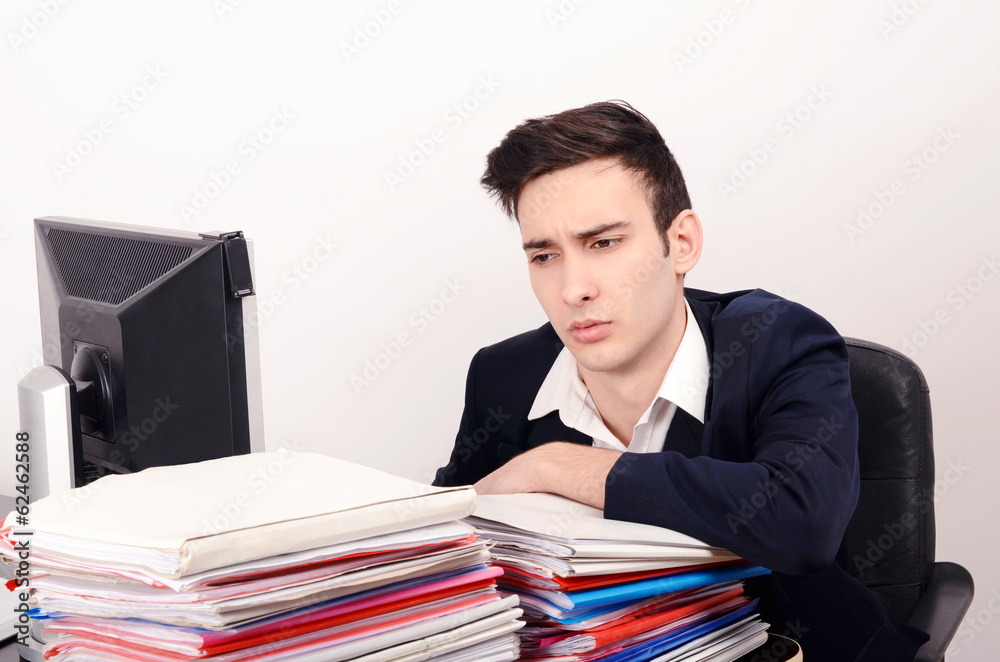 Bored worried business man with a big pile of files to work on Bored worried business man with a big pile of files to work on