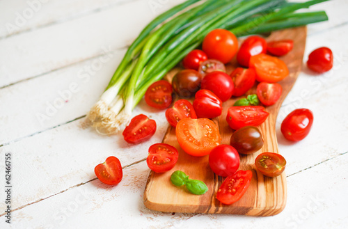 Colorful tomatoes on board on wooden background