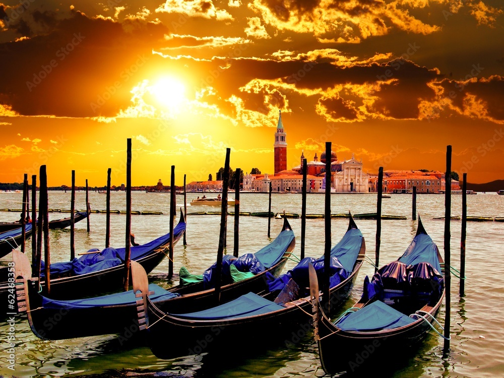 Vibrant sunrise over the lagoon of Venice, Italy with gondolas