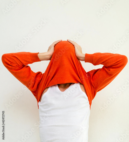 Funny portrait of man in sweater on head against white wall