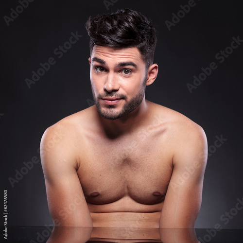 bare chest young man raises his eyebrows