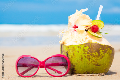 picture of fresh cocnut cocktail and red sunglasses on tropical