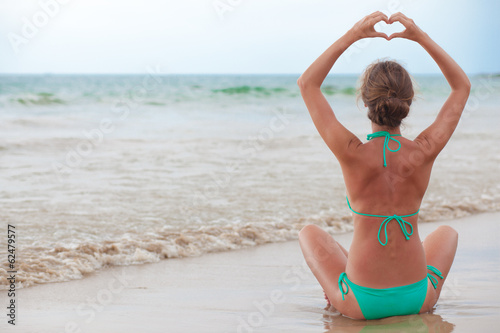 photo back view young woman in bikini posing on beach