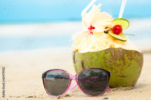 picture of fresh cocnut cocktail and pink sunglasses on tropical