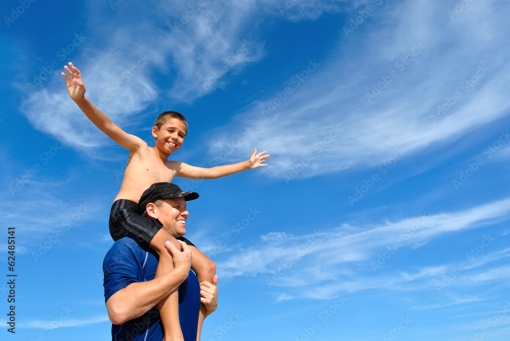 Son balancing on dad's shoulders Son balancing on dad's shoulders