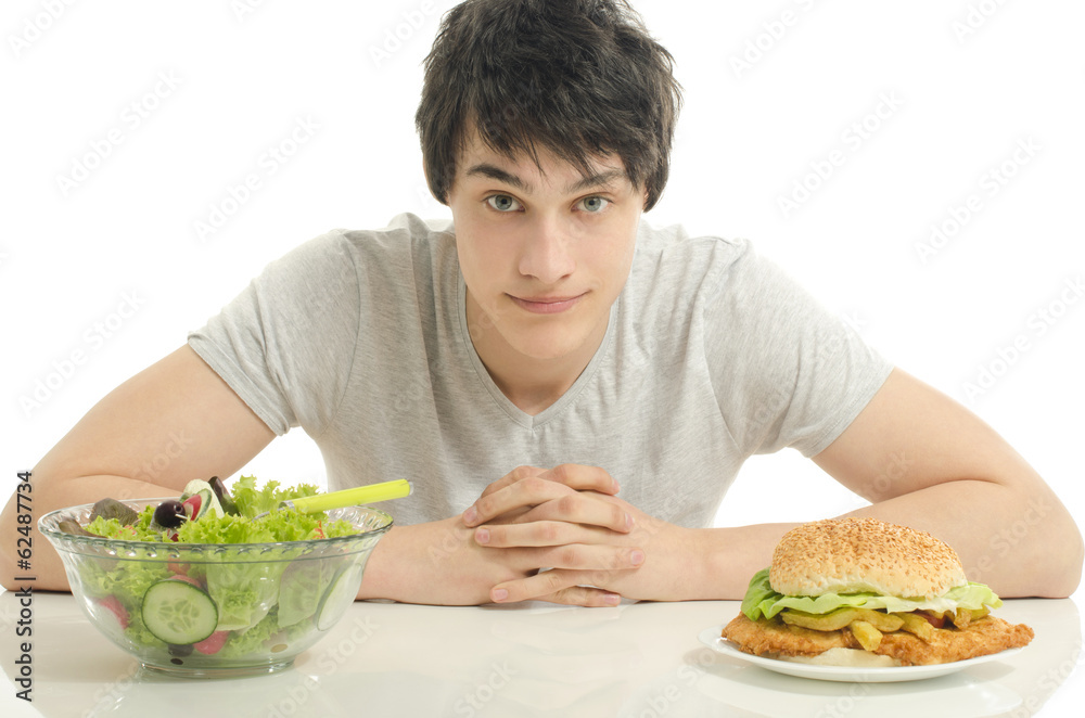 Young man holding in front a bowl of salad and a big hamburger. Young man holding in front a bowl of salad and a big hamburger.