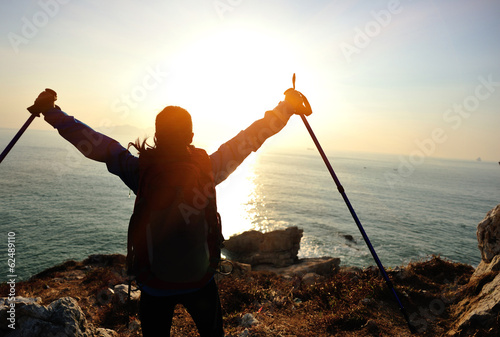 cheering woman hiker open arms at sunrise seaside photo