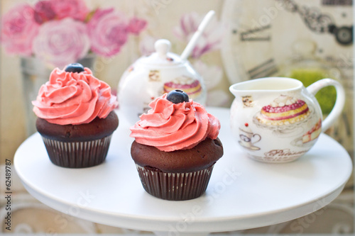 Chocolate cupcakes with pink frosting and blueberries with elegant sausepan on the background photo