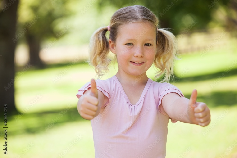 Smiling girl gesturing thumbs up at park Smiling girl gesturing thumbs up at park