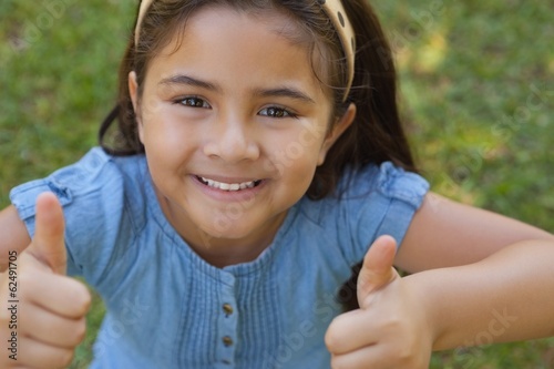 Young girl gesturing thumbs up at park