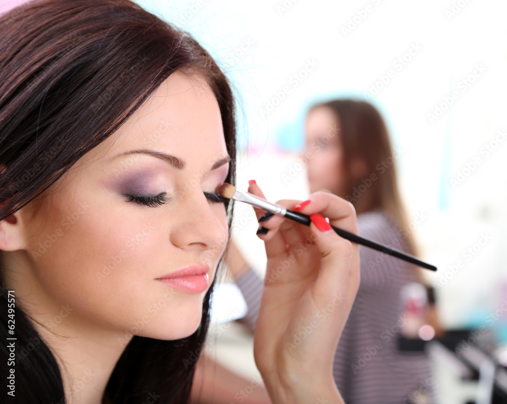 Young woman stylist doing makeup beautiful girl in beauty salon Young woman stylist doing makeup beautiful girl in beauty salon