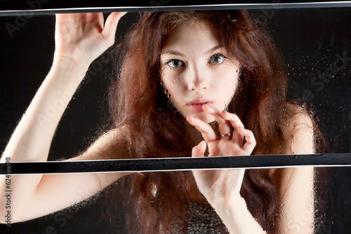 girl behind wet glass on dark background