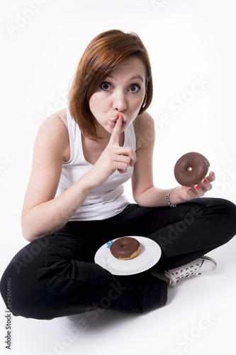 red hair woman secretly eating a chocolate donut on white backgr