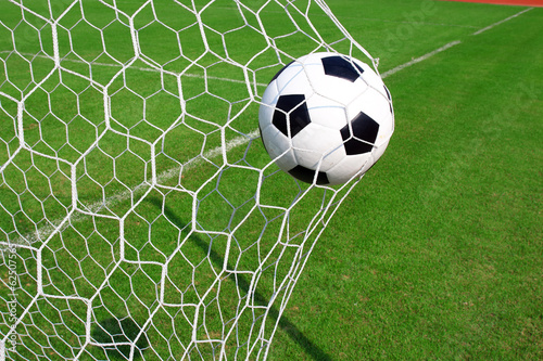 Soccer football in Goal net with green grass field © joesive47