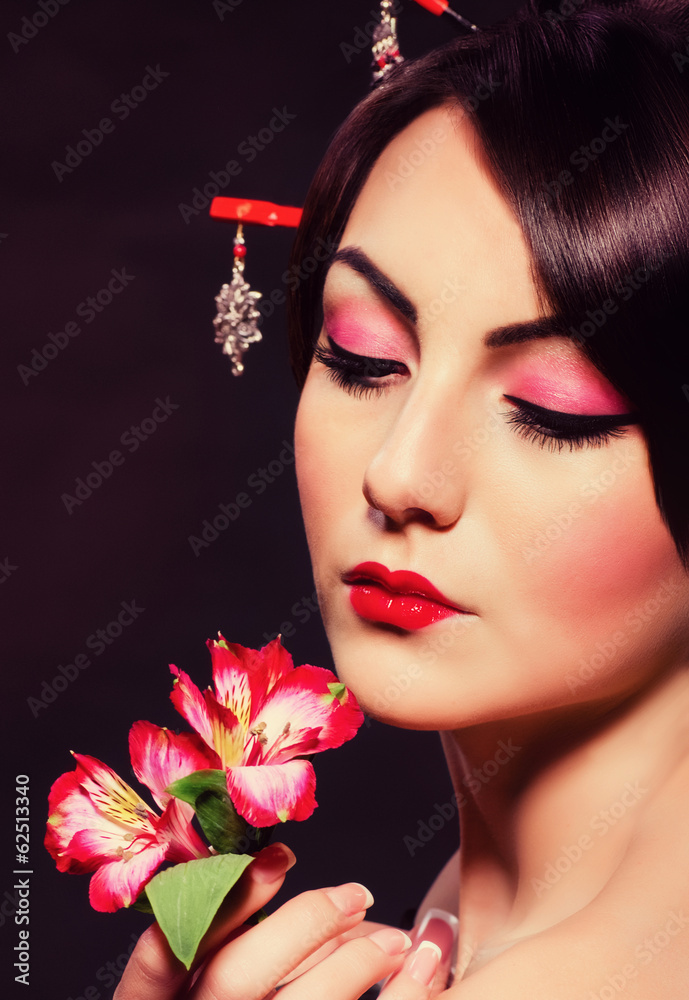 Beautiful woman in Asian costume with red flowers on black Beautiful woman in Asian costume with red flowers on black