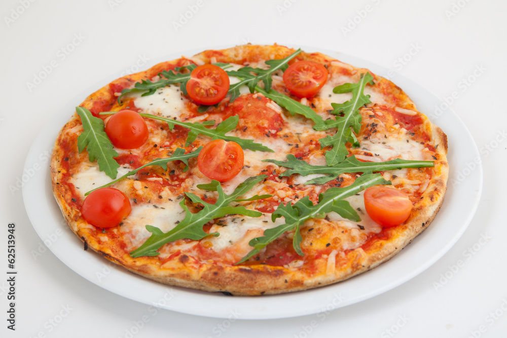 Pizza with tomato and arugula on white plate