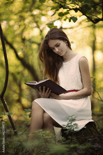 young beautiful girl with book in the forest