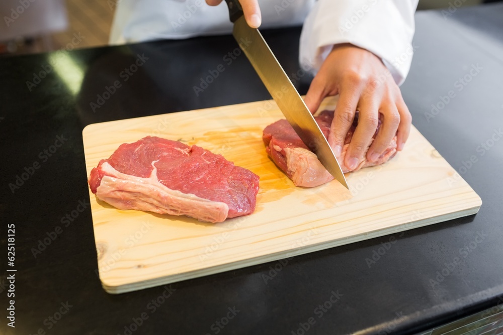 Mid section of hands cutting meat