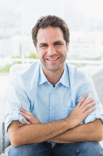 Cheerful man sitting on the couch smiling at camera