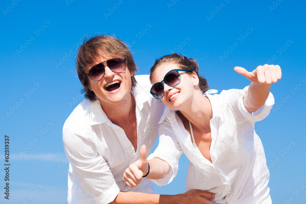 Front view of happy young couple on beach smiling and hugging