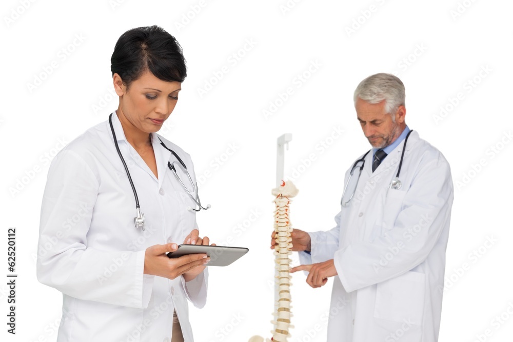Doctor holding digital table with colleague by skeleton model Doctor holding digital table with colleague by skeleton model