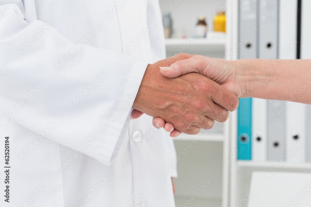 Mid section of a doctor shaking hands with patient Mid section of a doctor shaking hands with patient
