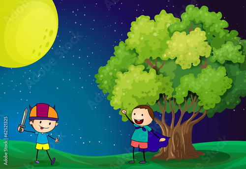 Happy kids playing near the tree under the bright fullmoon
