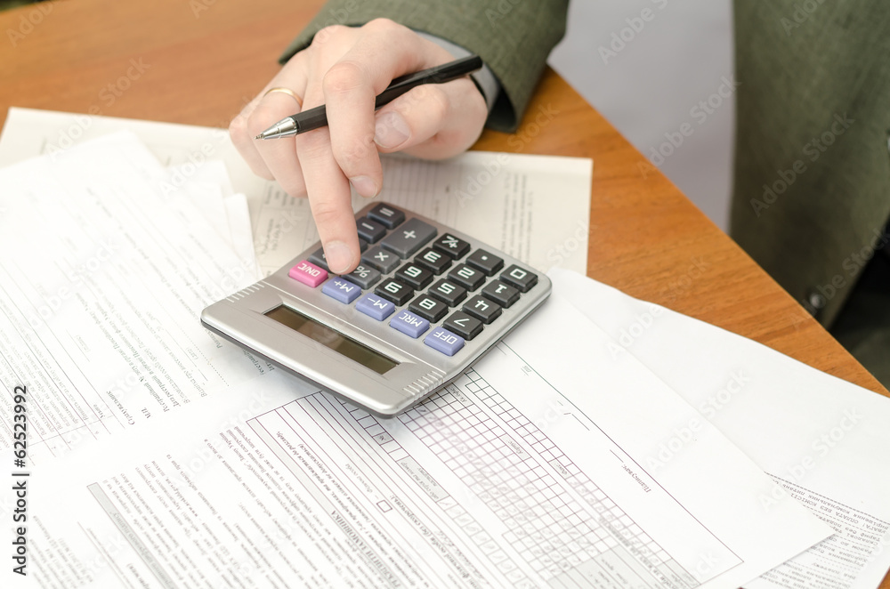 the businessman during office work with documents and the calcul the businessman during office work with documents and the calcul