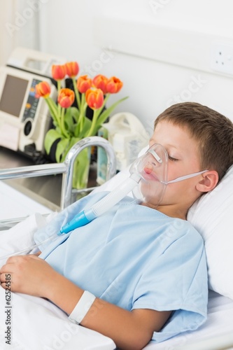 Boy wearing oxygen mask in hospital bed