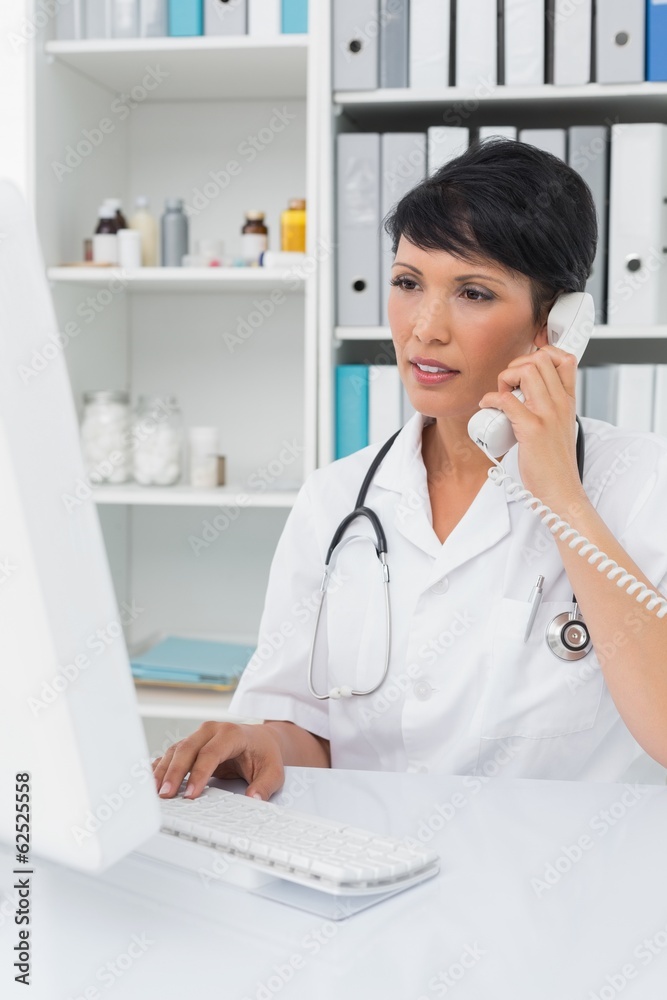 Concentrated doctor using computer and telephone Concentrated doctor using computer and telephone