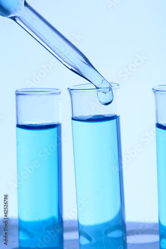 Dropper and test tubes, close up, on blue background