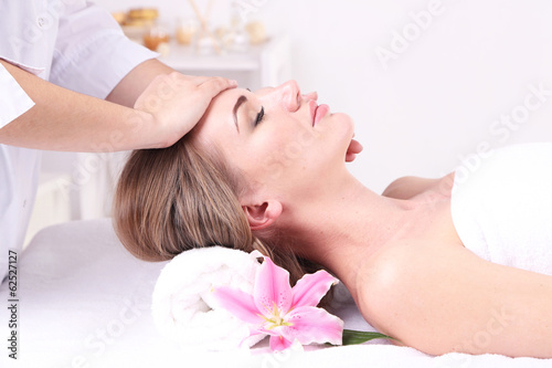 Beautiful young woman having head massage in spa salon,
