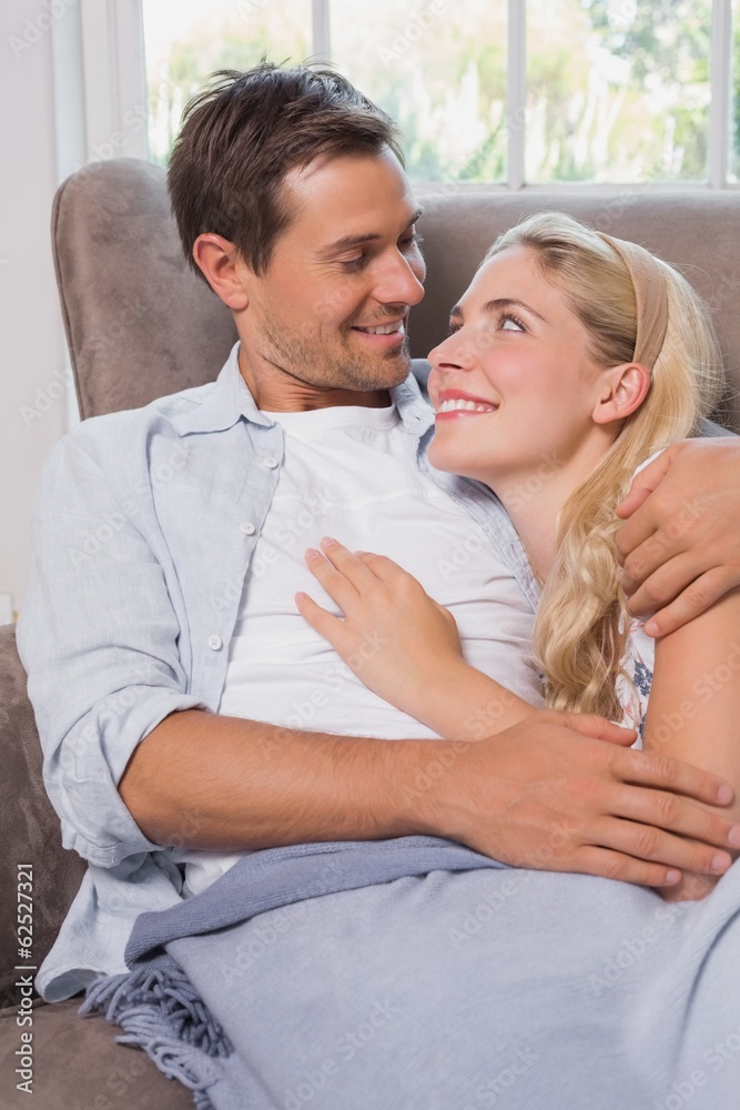Loving couple looking at each other while lying on sofa Loving couple looking at each other while lying on sofa