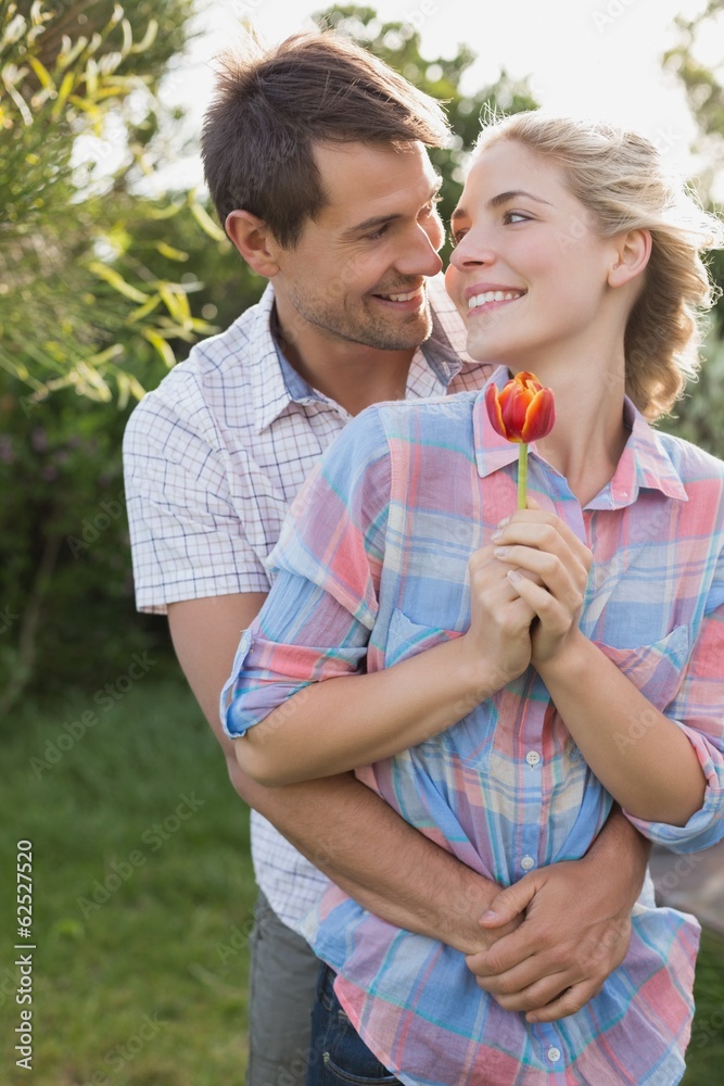 Fototapeta premium Young couple holding a flower in the park