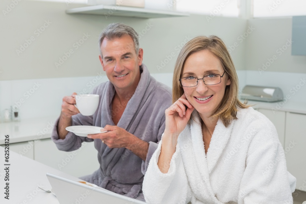 Couple having breakfast while using laptop in kitchen Couple having breakfast while using laptop in kitchen