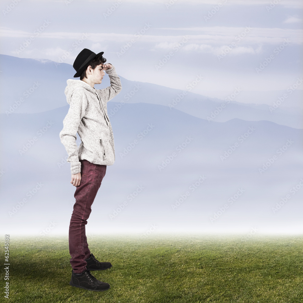 teenager on grass landscape with mountains at the horizon