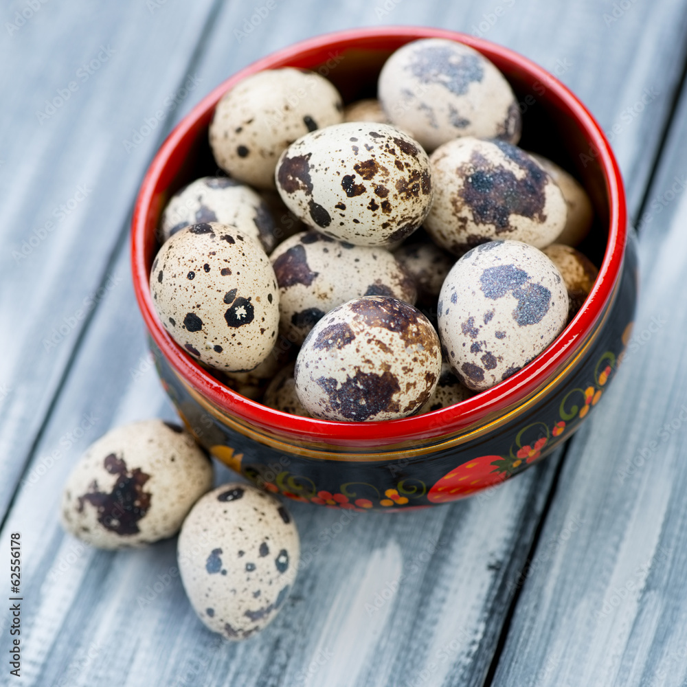 Wooden khokhloma bowl with raw quail eggs, studio shot Wooden khokhloma bowl with raw quail eggs, studio shot