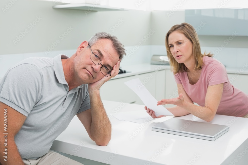 Couple having an argument over a bill in kitchen Couple having an argument over a bill in kitchen