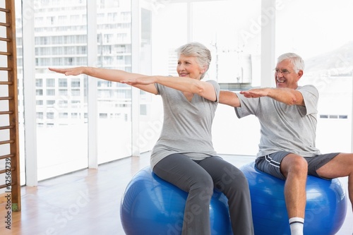 Senior couple doing stretching exercises on fitness balls