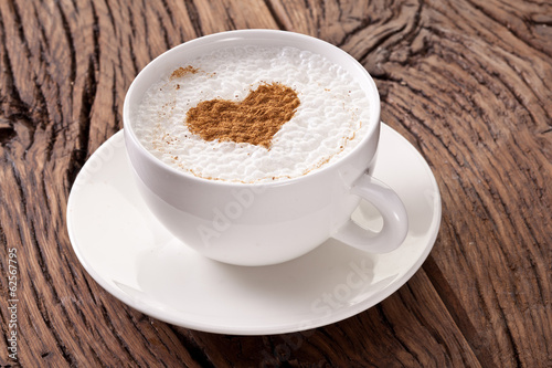 Cup of cappuccino with ground cinnamon in the form of heart.