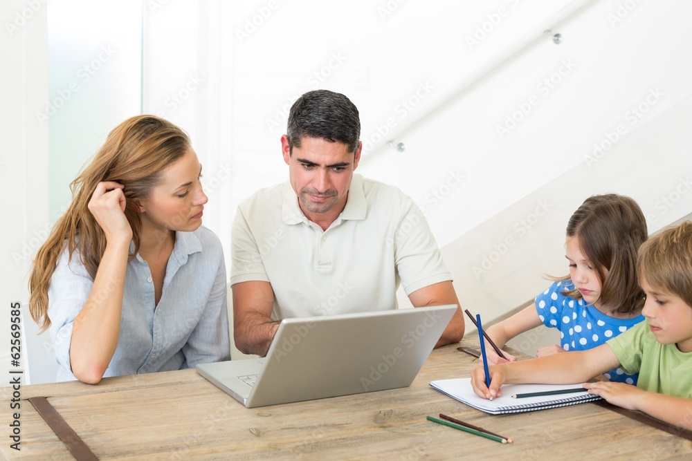 Parents using laptop while children coloring Parents using laptop while children coloring