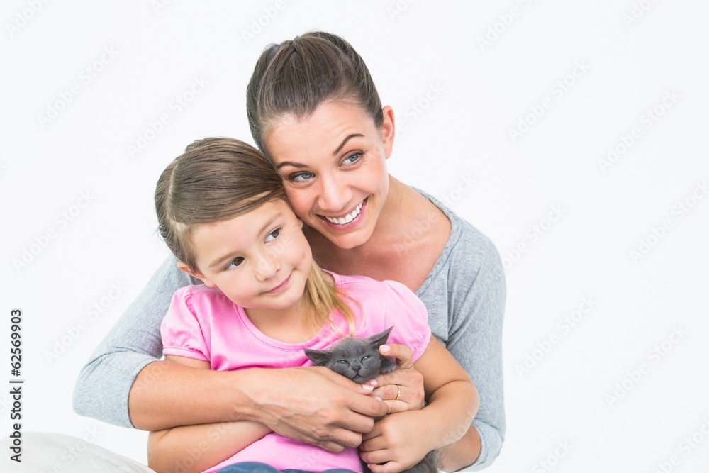 Happy mother and daughter sitting with pet kitten together Happy mother and daughter sitting with pet kitten together