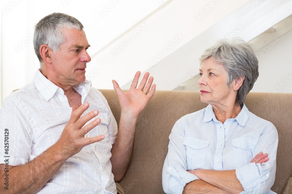 Senior couple sitting on couch having an argument Senior couple sitting on couch having an argument