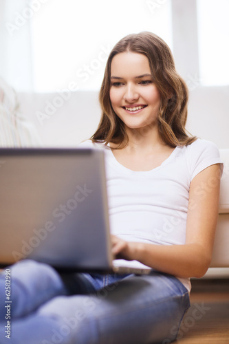 smiling teenage girl with laptop computer at home