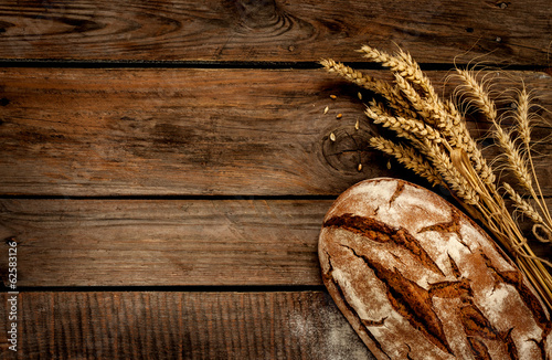 Photo Rustic bread and wheat on vintage wood table