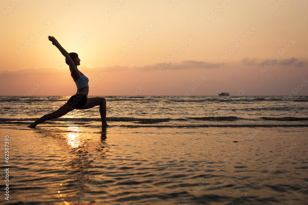 Fototapeta premium Yoga silhouette on the beach, virabhadrasana pose